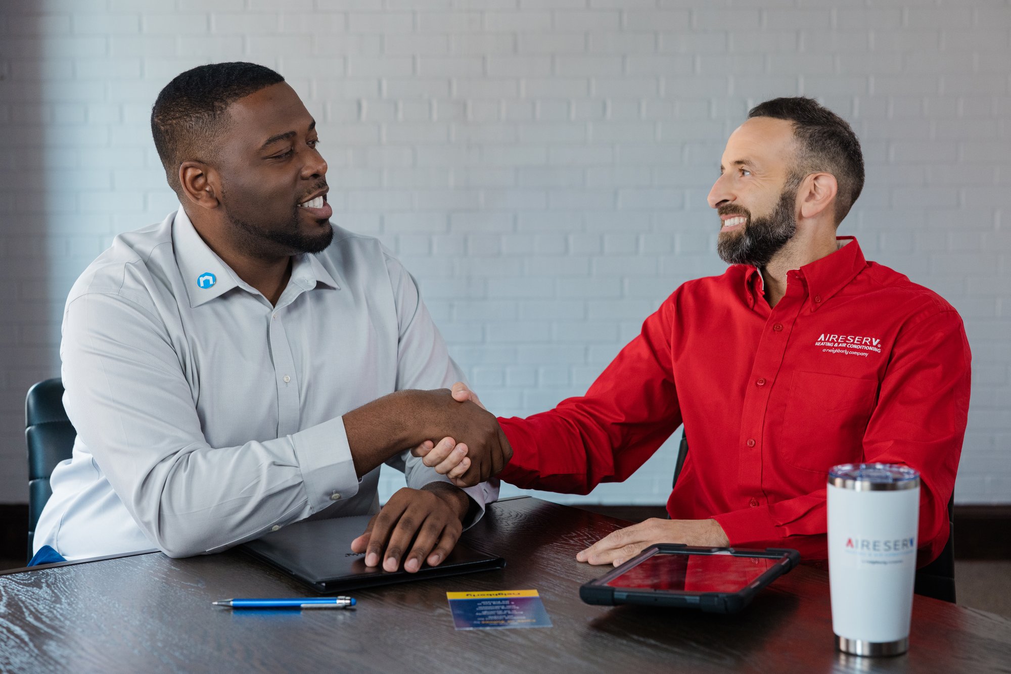 Aire Serv coach and franchise owner shaking hands during a one‑on‑one training session, highlighting the brand’s strong coaching, support, and business development guidance.